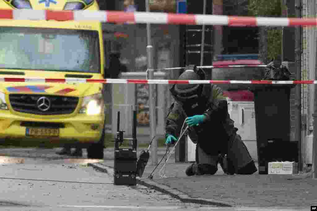 A member of the Explosive Ordnance Disposal team, EOD, examines a suspect package after it was found on the doorstep of Kosher restaurant HaCarmel in Amsterdam, Netherlands.