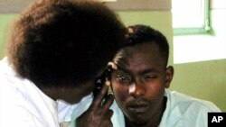 FILE - A nurse examines the eyes of John Kabiru Njenga in Kenyatta National Hospital in Nairobi, where he was admitted after drinking home brewed alcohol.