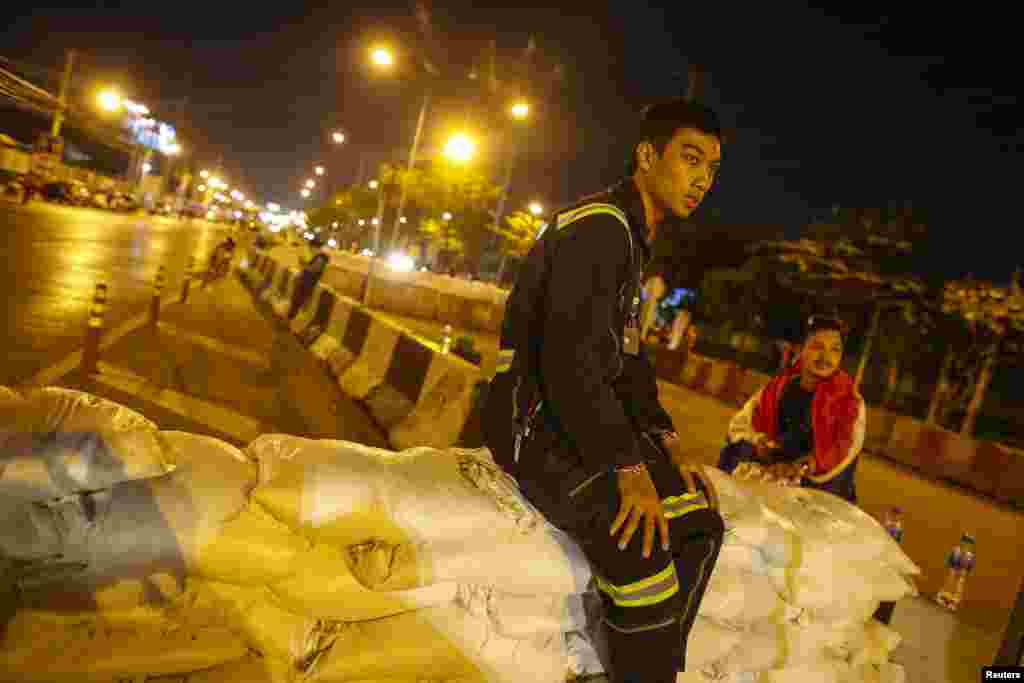 A rescue worker sits on a barricade after anti-government protesters close the road near Government Complex, Bangkok, Jan. 12, 2014. 