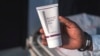 FILE - Aranmolate Ayobami, plastic surgeon at Grandville Medical and Laser clinic in Lagos, holds a tube of Skinlite a skin lightening product used at his clinic, on July 17, 2018, in Lagos, Nigeria.