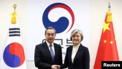 Menteri Luar Negeri China, Wang Yi (kiri) berjabat tangan dengan Menlu Korea Selatan, Kang Kyung-wha (kanan) di kantor Kementerian Luar Negeri Korsel, Seoul, 4 Desember 2019. 