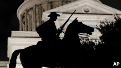 The Terry's Texas Rangers cavalry monument, a regiment of Texas volunteers for the Confederate States Army assembled by Colonel Benjamin Franklin Terry in August 1861, is silhouetted against the Texas State Capitol in Austin, Texas, Aug. 21, 2017.