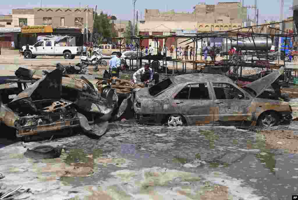 Iraqi security forces inspect wrecks of destroyed cars at the site of a car bomb attack in Basra, Sept. 15, 2013.