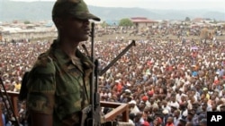 A soldier from the M23 rebel group looks on as thousands of Congolese people listen during an M23 rally, in Goma, eastern Congo, Nov. 21, 2012