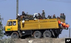 Syrian army soldiers sit aboard a truck near the village of Sh.Miskin, Syria, Aug. 14, 2018.