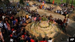 Local villagers pray surrounding the small sand hills, locally called "Sam-ang Phnom", praying to mark the end of Khmer New Year, from April 14 to 16, at Phneat Sampaly pagoda, on the outskirt of Phnom Penh, Thursday, April 17, 2014. (AP Photo/Heng Sinith)