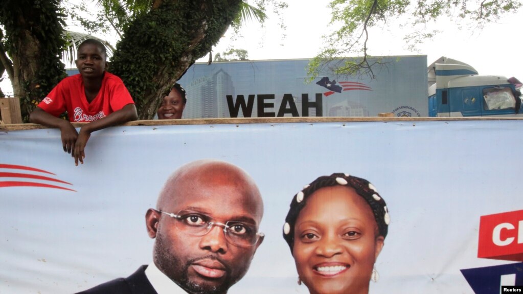 Un partisan de l'ancien footballeur et candidat à la présidence du Congrès pour le changement démocratique (CDC) George Weah se tient derrière une bannière de la campagne présidentielle à Monrovia, Libéria, le 6 octobre 2017.