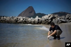 FILE - Fernando Spilki, virologist and coordinator of the environmental quality program at Feevale University, takes samples of water at the Marina da Gloria, in Rio de Janeiro, April 28, 2015.