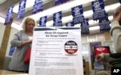 FILE - A sign tells voters of voter ID requirements before participating in the primary election at Sherrod Elementary school in Arlington, Texas, March 1, 2016.