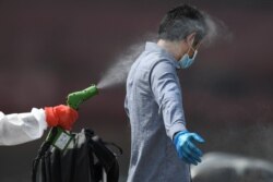 Seorang petugas kesehatan menyemprotkan disinfektan ke salah satu anak buah kapal (ABK) kapal pesiar Explorer Dream yang tiba di pelabuhan JCT, Jakarta, di tengah wabah virus corona, Jakarta, 29 April 2020. (Foto: Antara via Reuters)