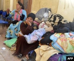 FILE - Egyptian Coptic Christians sit in the courtyard of the Evangelical Church in the Suez Canal city of Ismailiya, Feb. 24, 2017, upon arriving to take refuge from Islamic State group jihadists.