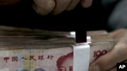 An employee seals a stack of yuan banknotes at a branch of Industrial and Commercial Bank of China in Huaibei, Anhui province April 6, 2011