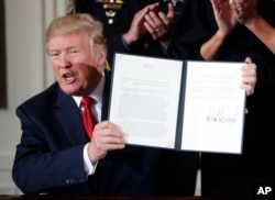 FILE - President Donald Trump displays a presidential memorandum he signed, declaring the opioid crisis a public health emergency, in the East Room of the White House, Oct. 26, 2017, in Washington.