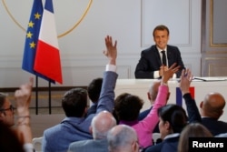 French President Emmanuel Macron reacts as journalists raise their hands to ask questions during a news conference to unveil his policy response to the yellow vests protest, at the Elysee Palace in Paris, April 25, 2019.