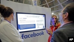 Laura Juanes Micas, of Facebook, center, talks to visitors about the how teaming data and social media can help people live healthier lives, at the Facebook booth, at eMerge Americas technology conference, at the Miami Beach Convention Center, Tuesday, Ju