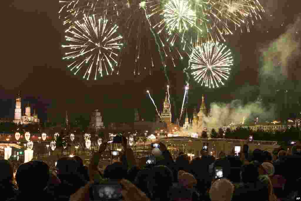 People take pictures as fireworks explode over the Kremlin, during New Year&#39;s celebrations in Moscow, Russia, Jan. 1, 2018.