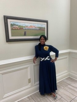 Courtney Tobias inside Life Tabernacle Church in Baton Rouge, posing in front of a photo of Pastor Tony Spell, his wife, and the church's bus fleet.