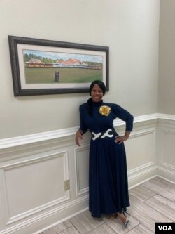 Courtney Tobias inside Life Tabernacle Church in Baton Rouge, posing in front of a photo of Pastor Tony Spell, his wife, and the church's bus fleet.