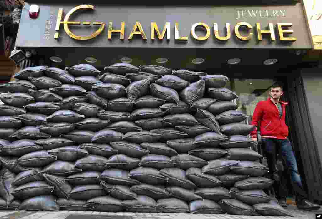 A Lebanese man walks past sand barriers that were set in front of a jewelry shop in a Shi&#39;ite neighborhood in a southern suburb of Beirut. After a wave of car bomb attacks on Hezbollah&#39;s stronghold south of Beirut that left scores of people dead or wounded over the past three months, shop owners scared of more bombs have set up sand barriers in front of their shops to reduce damage.