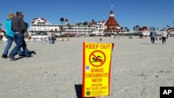 A sign warns of sewage contaminated ocean waters on a beach in front of the iconic Hotel del Coronado in Coronado, California, March 1, 2017.