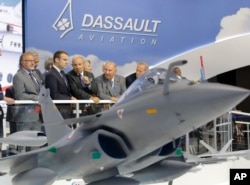 French President Emmanuel Macron, second left, listens to Dassault Aviation CEO Eric Trappier, center, while visiting the Paris Air Show in Le Bourget, June 19, 2017. Macron landed at the Bourget airfield in an Airbus A400-M military transport plane to launch the aviation showcase.