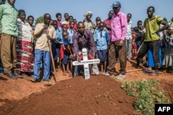 Mourners place a cross on the grave of Uwiringiyimana Gadi, 22, a victim of a collapsed mine, at the Ntunga public cemetery in Rwamagana, eastern Rwanda, on Jan. 22, 2019.