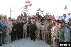 Iraqi Prime Minister Haider al-Abadi (C) holds an Iraqi flag as he announces victory over Islamic State in Mosul, July 10, 2017.