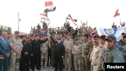 Iraqi Prime Minister Haider al-Abadi (C) holds an Iraqi flag as he announces victory over Islamic State in Mosul, Iraq, July 10, 2017. 