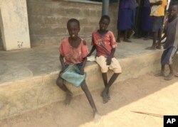Thor Athiam, 9, left, and his classmate eagerly wait with their lunchboxes for World Vision's daily hot meal in Rumathoil, South Sudan, April 6, 2017.