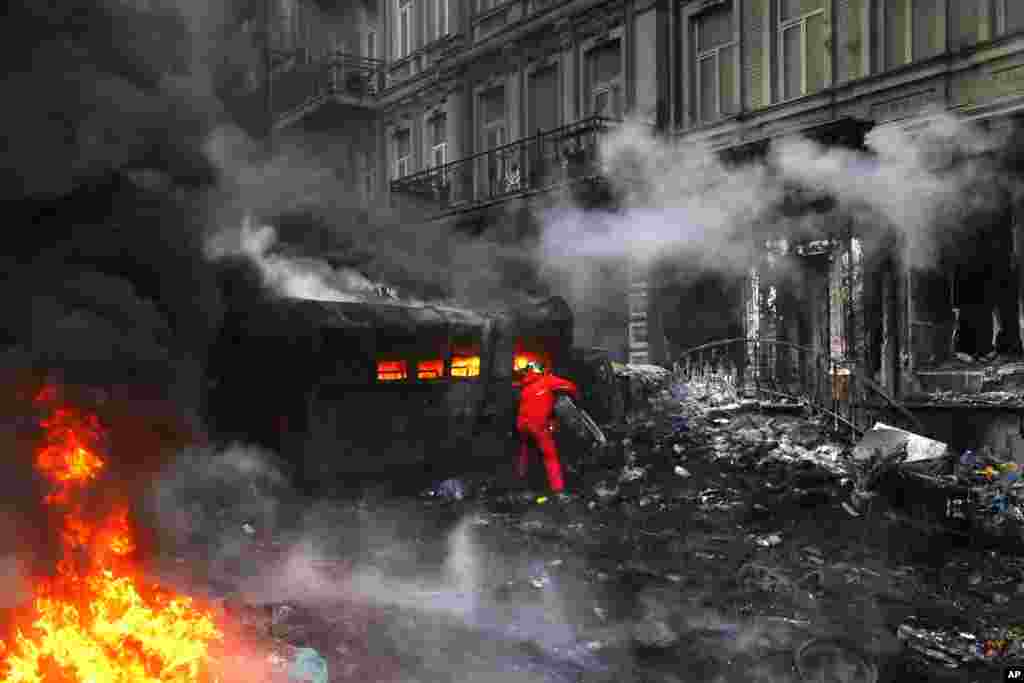 Um manifestante atira pneus para as chamas durante os confrontos com a polícia em Kiev, Jan. 23, 2014.