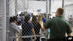 En esta foto suministrada por la Agencia de Aduanas y Protección Fronteriza de EE.UU., un agente de la Patrulla Fronteriza vigila a gente que ha sido detenida por ingresar ilegalmente al país en McAllen, Texas, el domingo, 17 de junio de 2018.