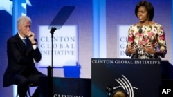 First Lady Michelle Obama (R) speaks while former President Bill Clinton (L) looks on during the closing plenary session of the annual Clinton Global Initiative (CGI) in New York City, 23 Sep 2010.