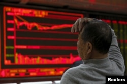 A man looks at an electronic board showing stock information at a brokerage house in Beijing, China, Jan. 4, 2016.