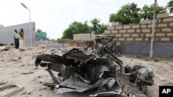 A damaged car is seen along a road after a bomb blast in Maiduguri in the northeastern state of Borno, June 29, 2011