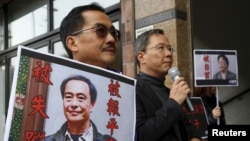 FILE - Pro-democracy Civic Party protesters carry portraits of missing booksellers Lee Bo, left, and Gui Minhai outside the Chinese Liaison Office in Hong Kong, Jan. 19, 2016.