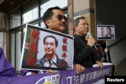 Pro-democracy Civic Party protesters carry portraits of missing booksellers Lee Bo, left, and Gui Minhai outside the Chinese Liaison Office in Hong Kong, Jan. 19, 2016.
