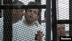 Al Jazeera's hunger-striking journalist Abdullah Elshamy stands behind bars with other prisoners at a court in Cairo, May 15, 2014.