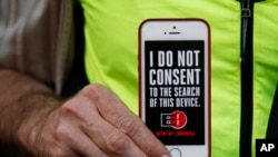 A man holds up his iPhone during a rally in support of data privacy outside the Apple store, Feb. 23, 2016, in San Francisco.