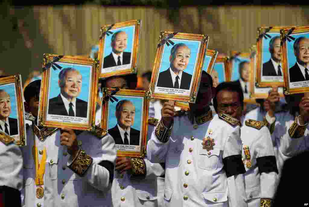 Procession participants shield themselves from the sun with portraits of the late former Cambodian King Norodom Sihanouk in a funeral procession in Phnom Penh.