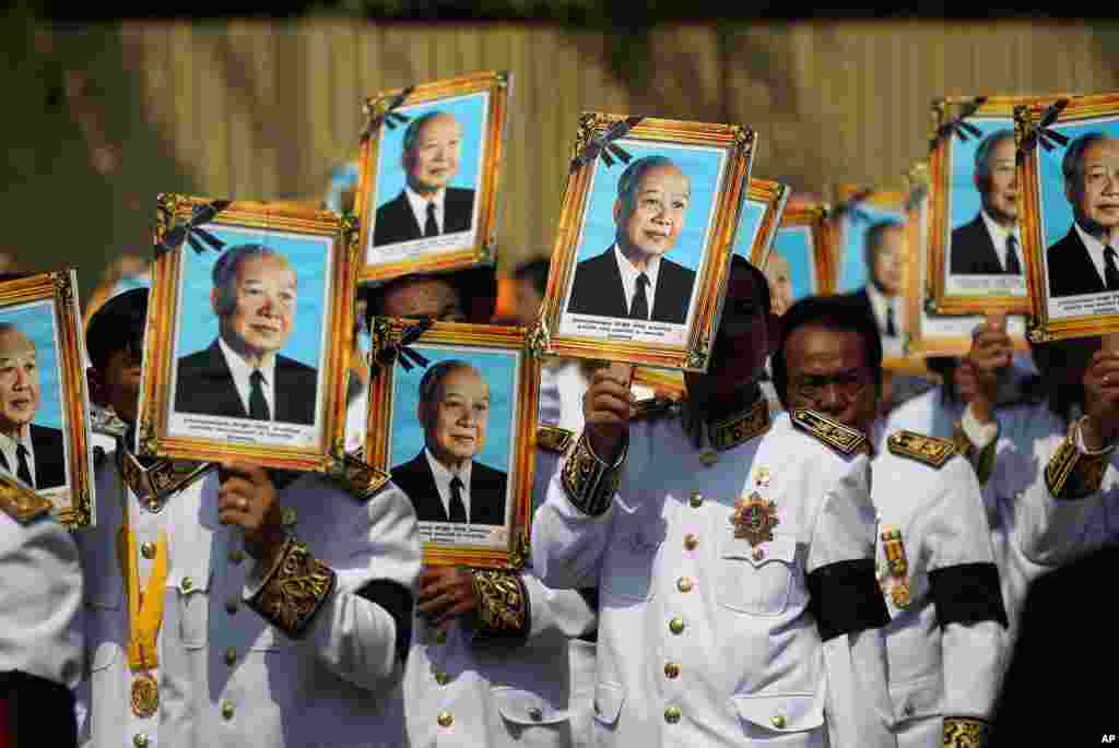 Procession participants shield themselves from the sun with portraits of the late former Cambodian King Norodom Sihanouk in a funeral procession in Phnom Penh. 