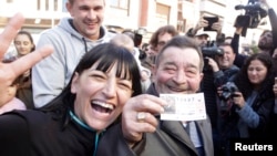 Juan Lopez holds his lottery ticket with the winning number of Spain's Christmas Lottery "El Gordo", together with his daughter Pilar in La Eliana near Valencia, Dec. 22, 2014.