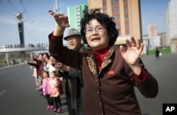 Sin Ye Suk, 50, a resident of Mirae Scientist Street stands in front of her apartment with fellow residents as they cheer on participants of the Pyongyang marathon, April 9, 2017, in Pyongyang, North Korea.