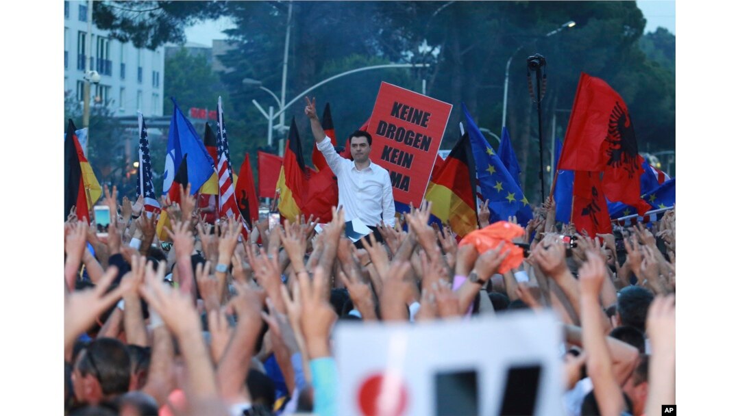 Lulzim Baša, lider najjače opozicione Demokratske stranke, stoji u pozadini pozdravljajući simbolom pobede tokom antivladinih protesta u Tirani, Albanija, 8. juna 2019.