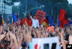 Lulzim Baša, lider najjače opozicione Demokratske stranke, stoji u pozadini pozdravljajući simbolom pobede tokom antivladinih protesta u Tirani, Albanija, 8. juna 2019.