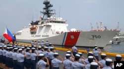 Philippine Coast Guard personnel salute to welcome the U.S. Coast Guard National Security Cutter Bertholf (WMSL 750) as it arrives for a port call in the first visit by a U.S. cutter in over seven years, Wednesday, May 15, 2019 in Manila, Philippines. (AP