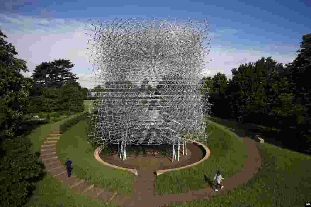 People pose for photographs by walking either side of artist Wolfgang Buttress&#39; 17 meter high bee health inspired &#39;The Hive&#39; aluminum installation as it stands on display after being put up in Kew Royal Botanic Gardens west London.