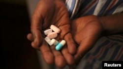 FILE - Nine-year-old Tumelo shows off antiretroviral (ARV) pills before taking his medication at Nkosi's Haven, south of Johannesburg, Nov. 28, 2014. 