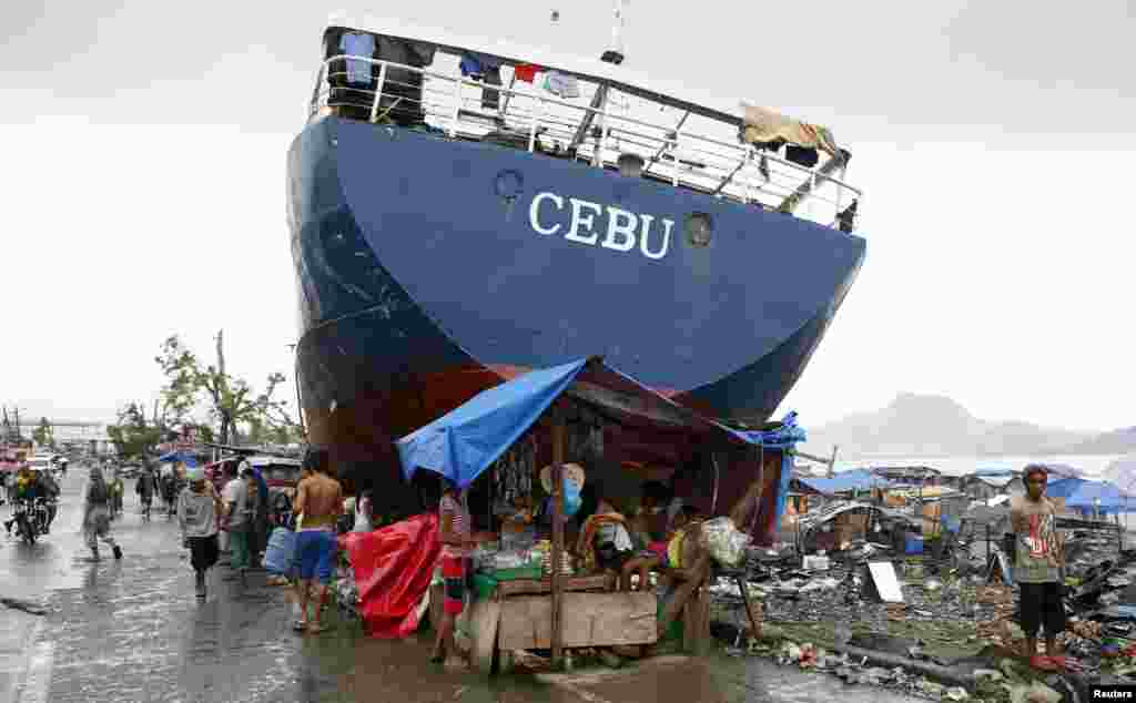 Korban selamat topan Haiyan di Filipina membuat tenda untuk menjual barang-barang dagangan di dekat sebuah kapal yang terdampar akibat hantaman topan di kota Tacloban. 