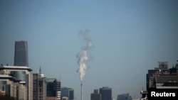 FILE - Steam billows from a chimney of a heating plant near the World Trade Centre Tower III, a 330-meter-tall (1,083 feet) skyscraper, in central Beijing. 