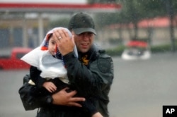 Sgt. Chad Watts of the Louisiana Department of Wildlife and Fisheries holds Madelyn Nguyen, 2, after he rescued her and her family by boat from floodwaters of Tropical Storm Harvey, in Houston, Aug. 28, 2017.